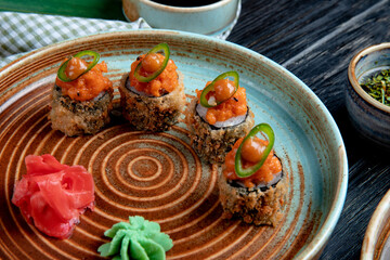 side view of set of baked sushi rolls with wasabi and ginger on a plate