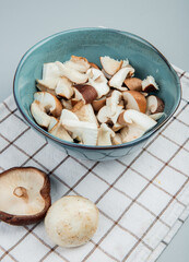 side view of sliced mushrooms in a bowl on plaid napkin on light blue background