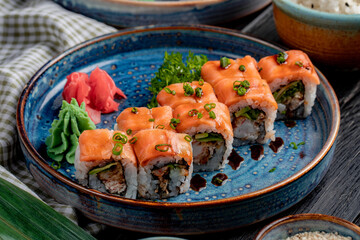 side view of sushi rolls with salmon eel avocado and cream cheese on a plate with ginger and wasabi