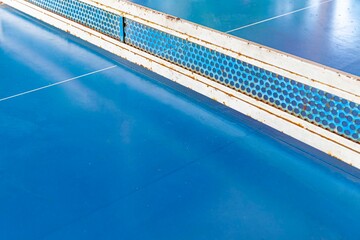 Obraz premium Close - up of empty blue wooden table tennis or ping-pong table without players