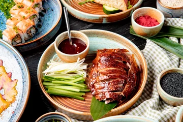 Keuken foto achterwand Peking zijaanzicht van traditioneel Aziatisch eten pekingeend met komkommers en saus op een bord