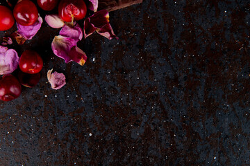 top view of  fresh red cherries with rose petals on dark background with copy space
