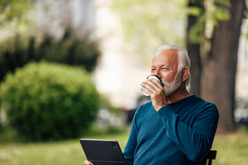Mature man, relaxing in the park, while taking a break from work.
