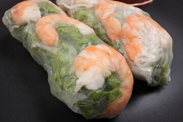 Vietnamese prawn shrimp see through rice paper spring roll green vegetable sauce on dark plate