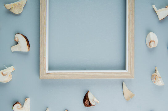 top view of an empty picture frame and sliced mushrooms on light blue background with copy space