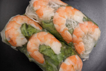 Vietnamese prawn shrimp see through rice paper spring roll green vegetable sauce on dark plate