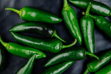 top view of fresh green chili peppers on black background
