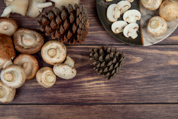Fototapeta na wymiar top view of fresh mushrooms and cones on rustic wooden background