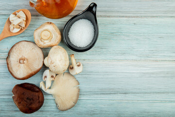 top view of fresh mushrooms bottle of olive oil and salt on rustic wooden background with copy space