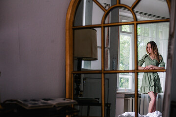 Fototapeta na wymiar Young, slender girl reflected in an old mirror