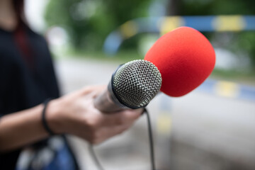 Journalist at news conference, writing notes, holding microphones