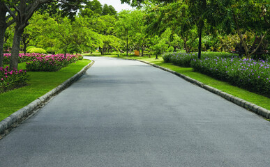 A walkway or jogging track in a park with blooming flowers.