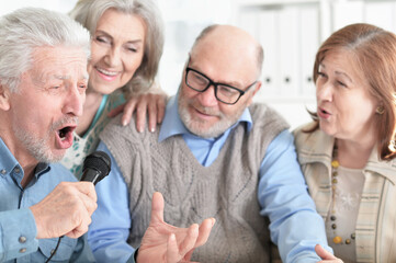 two senior couples singing karaoke with microphone