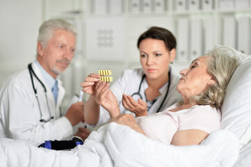Senior woman in hospital with caring doctors