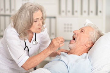 Obraz premium Senior man portrait in hospital with caring doctor