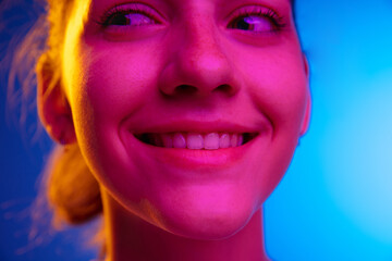 Caucasian young woman's portrait on dark studio background in neon. Concept of human emotions, facial expression.