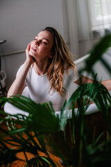 Naklejka premium A young, slender girl in a bodysuit in the middle of the room lies in the bathtub