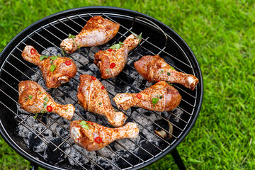 Chicken Drumsticks Legs Grilled on Charcoal BBQ in Backyard Garden at Summer Picnic