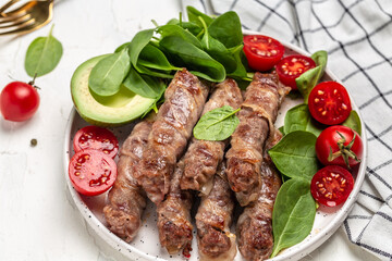 Ketogenic diet, minced meat rolls wrapped in bacon with spinach, avocado and cherry tomato, Healthy food
