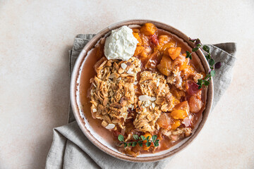 Ceramic plate with tasty plum crumble dessert served with vanilla ice cream and herbs. Top view.