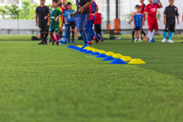 Obraz premium Soccer ball tactics on grass field with barrier for training children jump skill