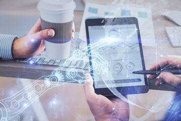 Double exposure of man's hands holding and using a digital device and tech theme hologram drawing....