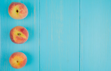 top view of fresh ripe peaches lined in a row on blue background with copy space