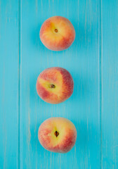 top view of fresh ripe peaches lined in a row on blue background