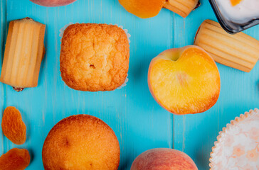 top view of fresh ripe peaches with muffins and biscuits on blue background