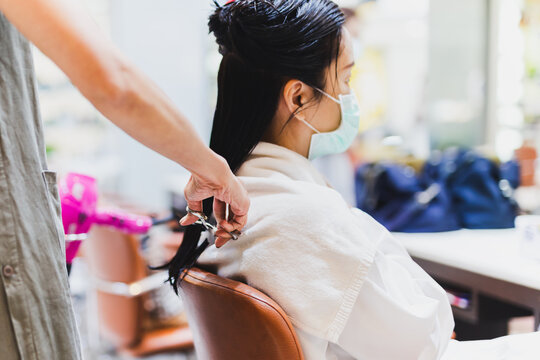 Woman hairdresser with scissors starting to cut client hair.