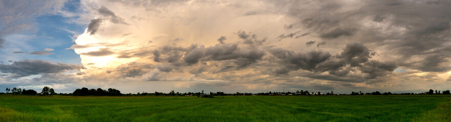 Fototapeta premium Panorama Dark sky and dramatic black cloud before rain.rainy storm over rice fields with rural road,Sisaket province,Thailand.
