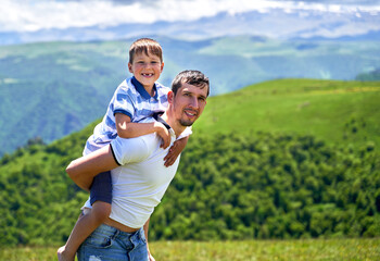 a child rides on his father's back