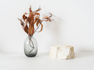 Grey natural stone podium on white background, platform for product display and autumn branches in...