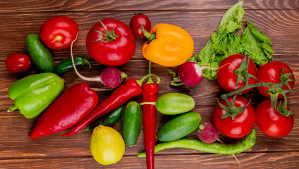 top view of fresh vegetables colorful bell peppers radish cucumbers tomatoes red chili peppers and lettuce on wooden rustic background