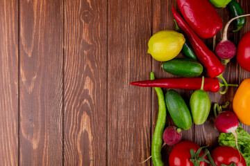 top view of fresh vegetables ripe tomatoes cucumbers green chili peppers lemon and radish on wooden rustic background with copy space