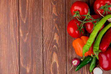 top view of fresh vegetables ripe tomatoes green chili peppers colorful bell peppers and radish on wooden rustic background with copy space