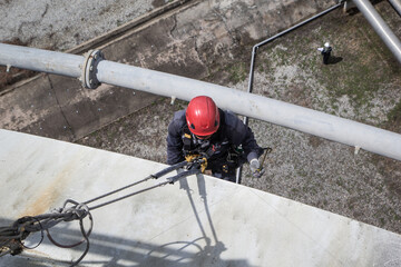Top view male worker rope access  inspection of plumbness storage tank industry