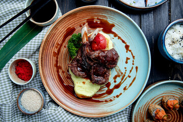 top view of mashed potatoes with roasted lamb chops and vegetables with soy sauce on a plate on wooden background