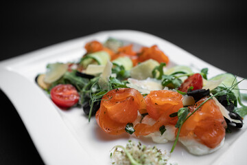 closeup of salad with lightly salted salmon and vegetables on black background