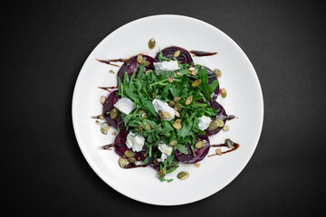 top view of healthy salad with beet, arugula and feta cheese on black background