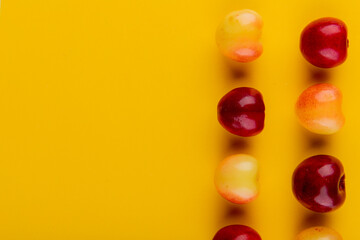 top view of ripe red and yellow cherries isolated on yellow background with copy space