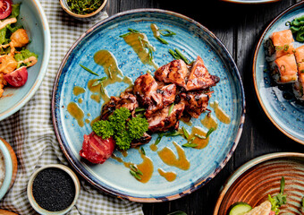 top view of roasted chicken with grilled tomato fresh herbs and sauce on a plate on wooden background