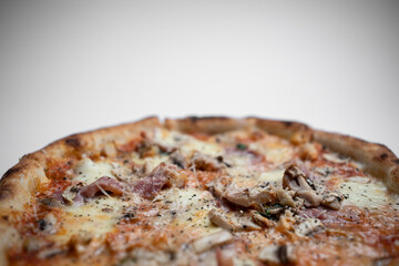 closeup of italian pizza with ham, mushrooms and cheese on white background