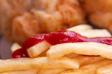 Close-up of food is easily blurred in soft focus. A plate of fries and fried chicken.