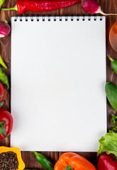 top view of sketchbook and fresh vegetables colorful bell peppers  green chili peppers tomatoes and black peppercorns on rustic wooden background
