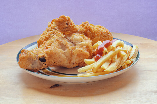 Plate With Several Fried Chicken Leg And Fries On A Wooden Background. Side View