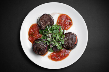 top view of meat beef medallion on tomato and grilled eggplant with salsa sauce