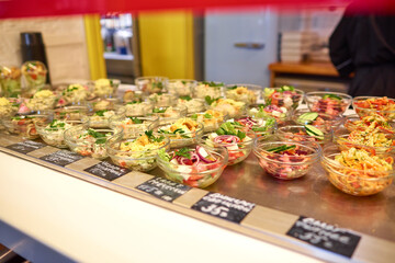 Various salads in glass round salad bowls - crab, Caesar with tomatoes, Greek