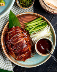 top view of traditional asian food peking duck with cucumbers and sauce on a plate