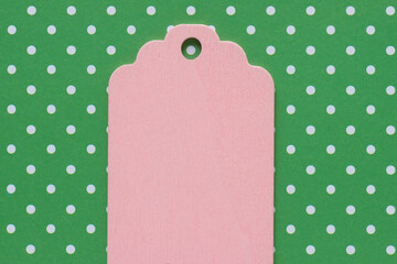 retro wooden pastel pink merchandise tag or label isolated on white and green polka dot patterned paper background